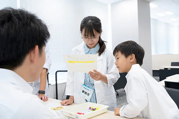 白衣を着た子供たちが薬剤師のお仕事を体験している様子