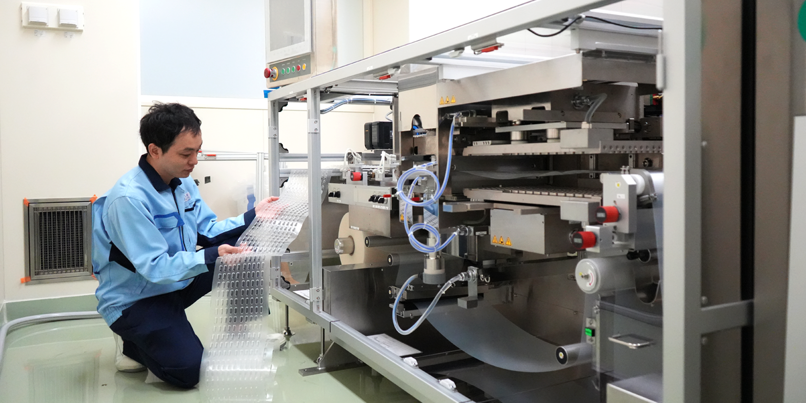 A team member inspecting PTP pockets on verification equipment for packaging material evaluation.